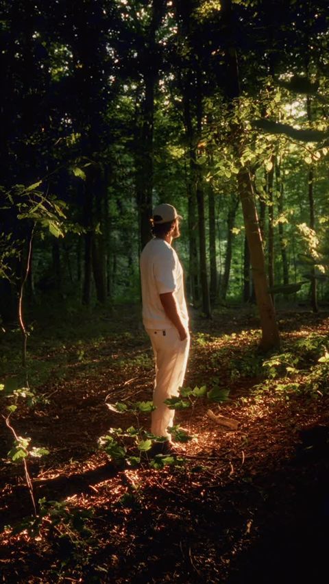 Zaid standing in a sunlit forest